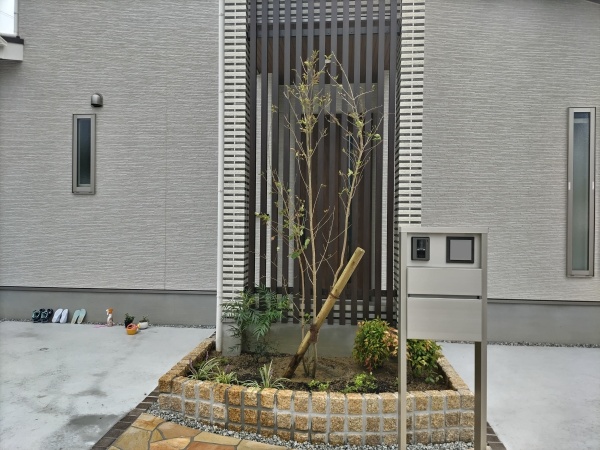 新築のエントランスの花壇に背の高いシンボルツリーと低い植木を植えた事例｜大阪市鶴見区A様（作業後）
